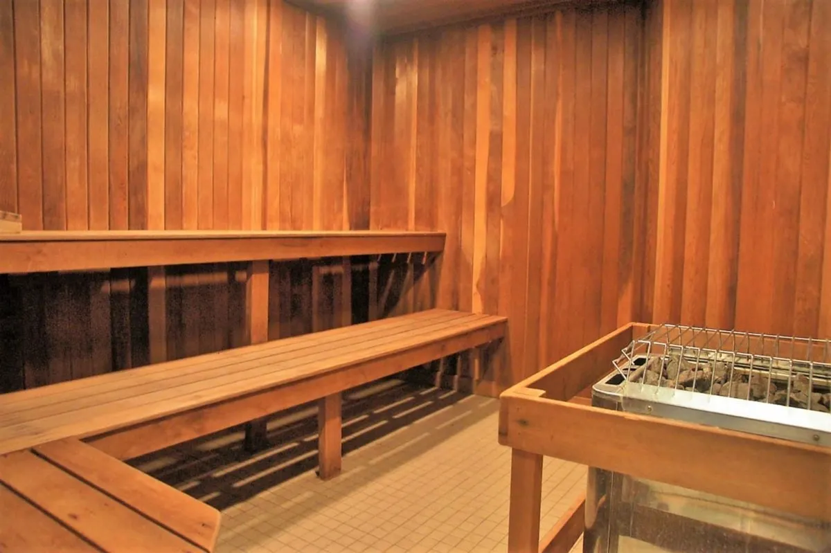 A warm, wood-paneled sauna with comfortable wooden benches and a traditional sauna heater, creating a peaceful retreat for guests seeking relaxation and a soothing escape.