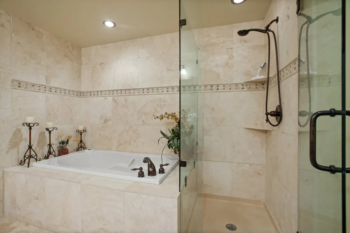 A modern, serene bathroom with a large bathtub, walk-in shower area, decorative candle holders, and a touch of greenery. The ambiance is tranquil, perfect for unwinding after a day of adventure.