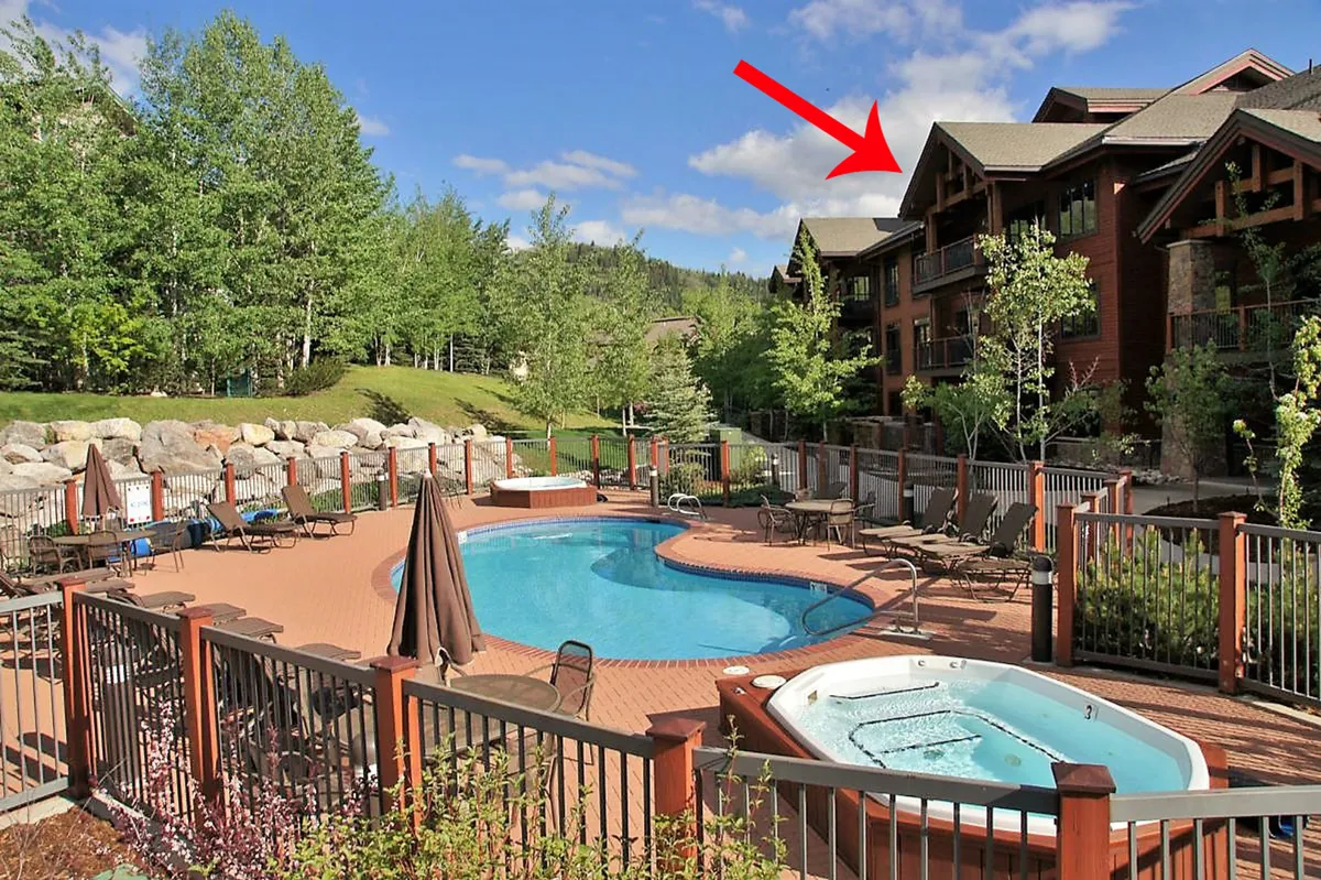 The image showcases the inviting outdoor amenities of Trappeur's Crossing Resort, featuring a sparkling swimming pool and bubbling hot tub surrounded by lush greenery and the balconies of upscale condo buildings. A warm sunset bathes the scene, suggesting a relaxed and sociable atmosphere where guests can unwind, socialize, and enjoy the Colorado mountain air.